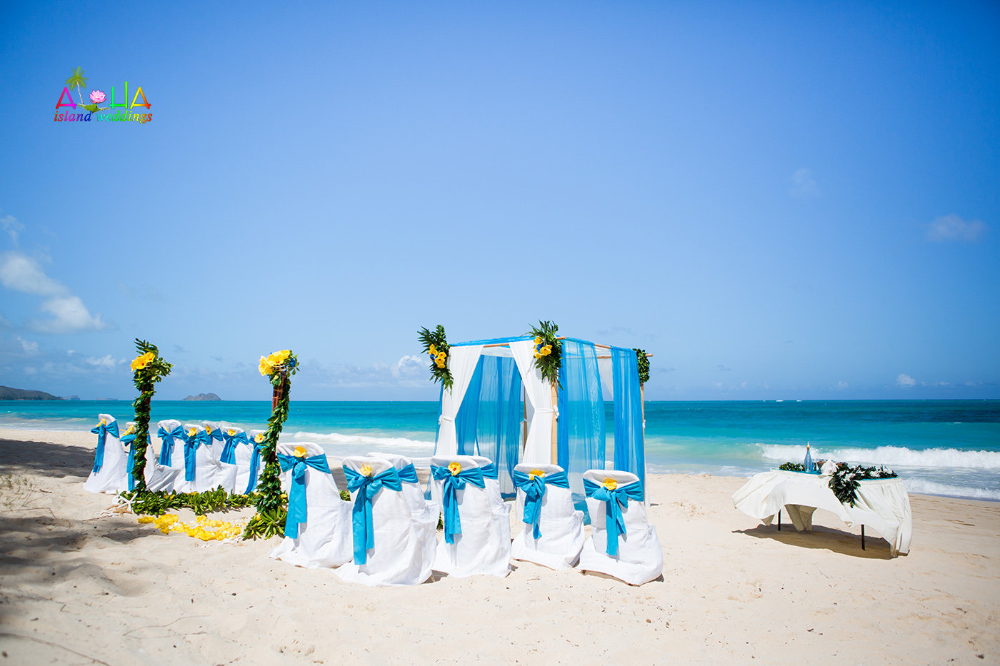 Waimanalo beach setup with blue and white drapes and yellow hibiscus